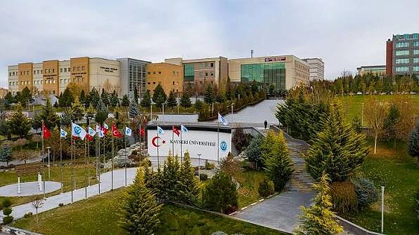 Kayseri Üniversitesi DGS Taban Puanları ve Kontenjanları Kayseri Üniversitesi kampüsü, yeşil alanlar ve bayraklarla çevrili modern binalar.