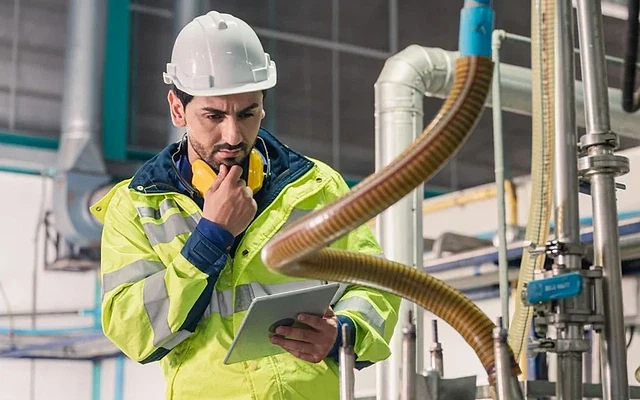 Eleman Nedir? İş İlanları ve Firmalar Fabrika ortamında tablet kullanan işçi, eleman arayışını simgeliyor.