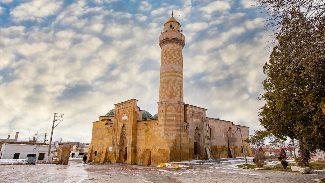 Niğde iş ilanları ve güncel fırsatlar Niğde'deki tarihi bir caminin dış görünümü, çevresinde karla kaplı zemin.